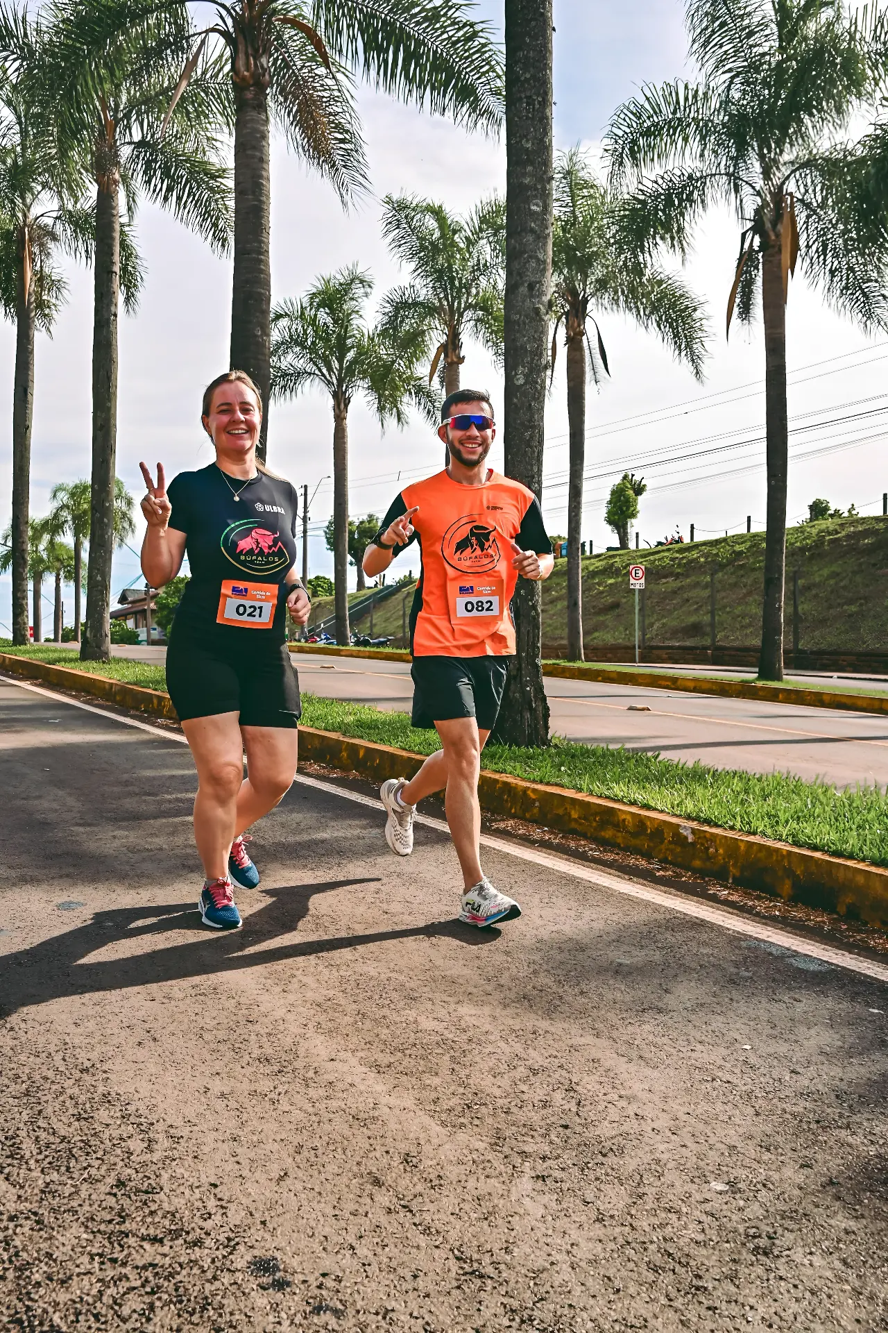 Dupla de alunos da Búfalos Team correndo entre palmeiras em prova de 5km