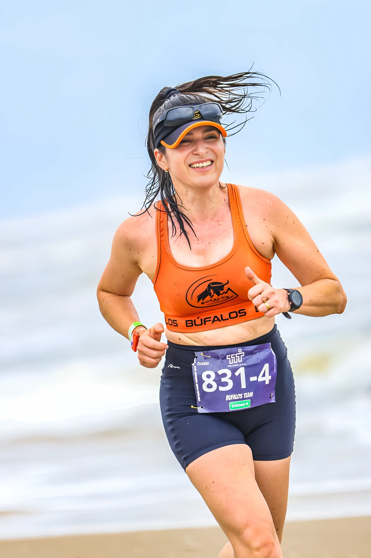 Aluna da Búfalos Team sorrindo durante corrida na praia