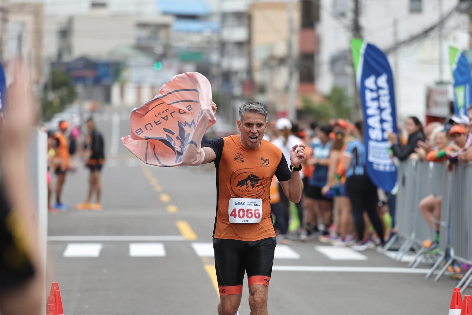 Atleta da Búfalos Team comemorando com a bandeira do time na chegada dos 42km