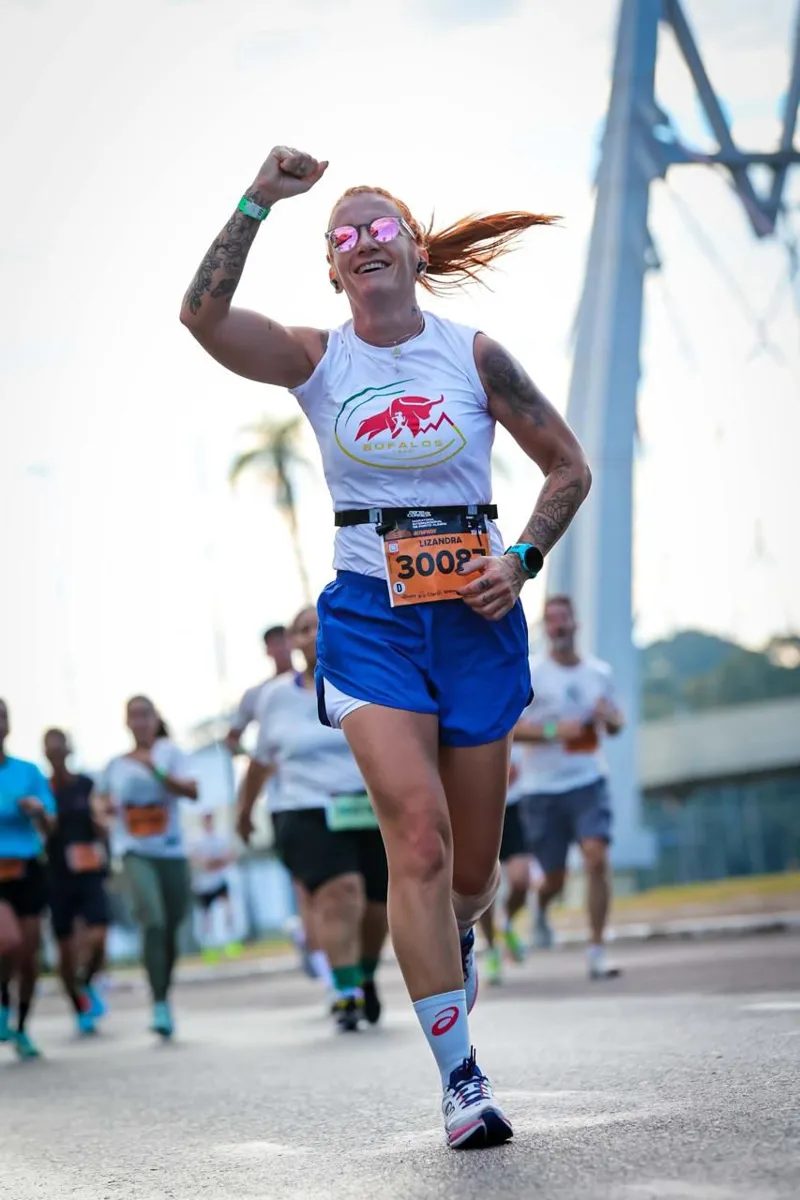 Aluna da Búfalos Team erguendo o punho e sorrindo durante a maratona