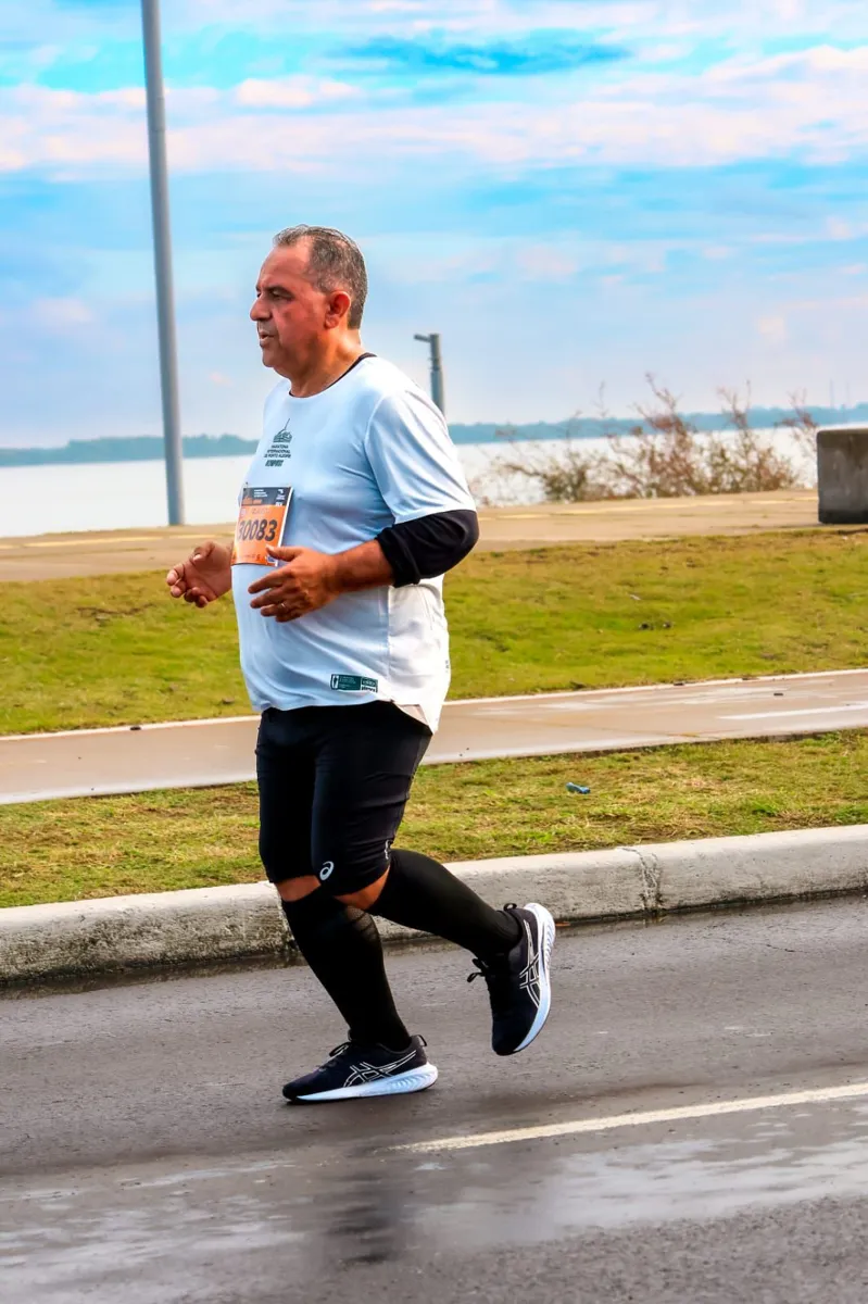 Aluno da Búfalos Team correndo na Maratona de Porto Alegre à beira do Guaíba