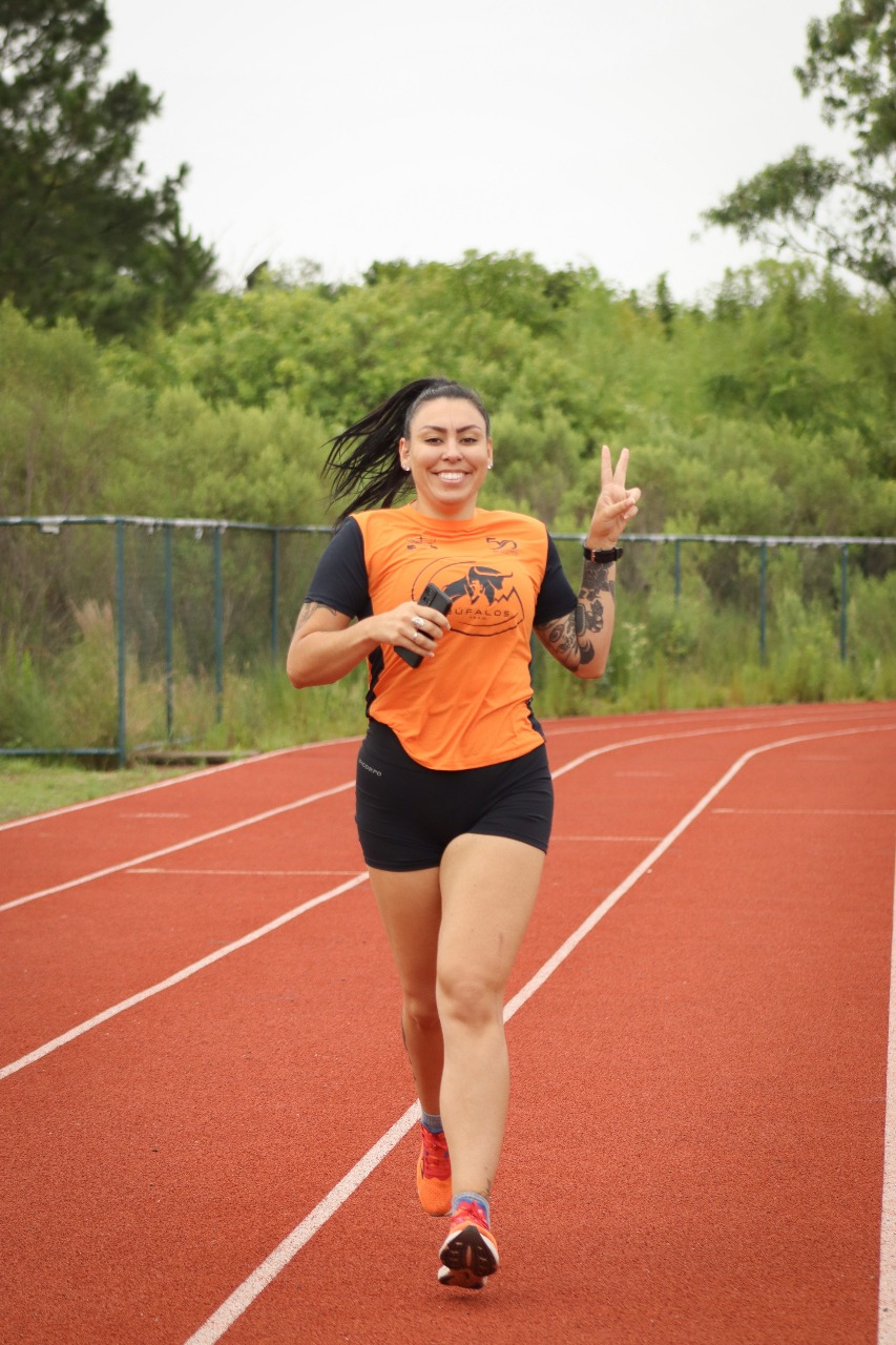 Corredora da Búfalos Team acelerando na pista de atletismo